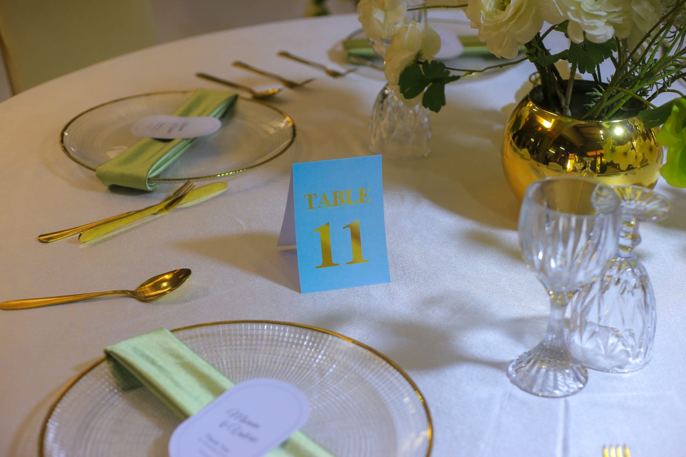 Table eleven laid for dinner with a gold vase centrepiece