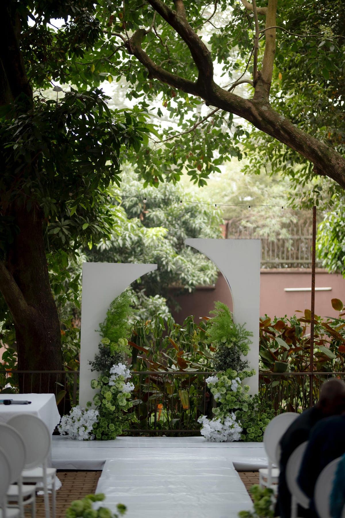 White ceremony arch dressed with greenery in a garden setting