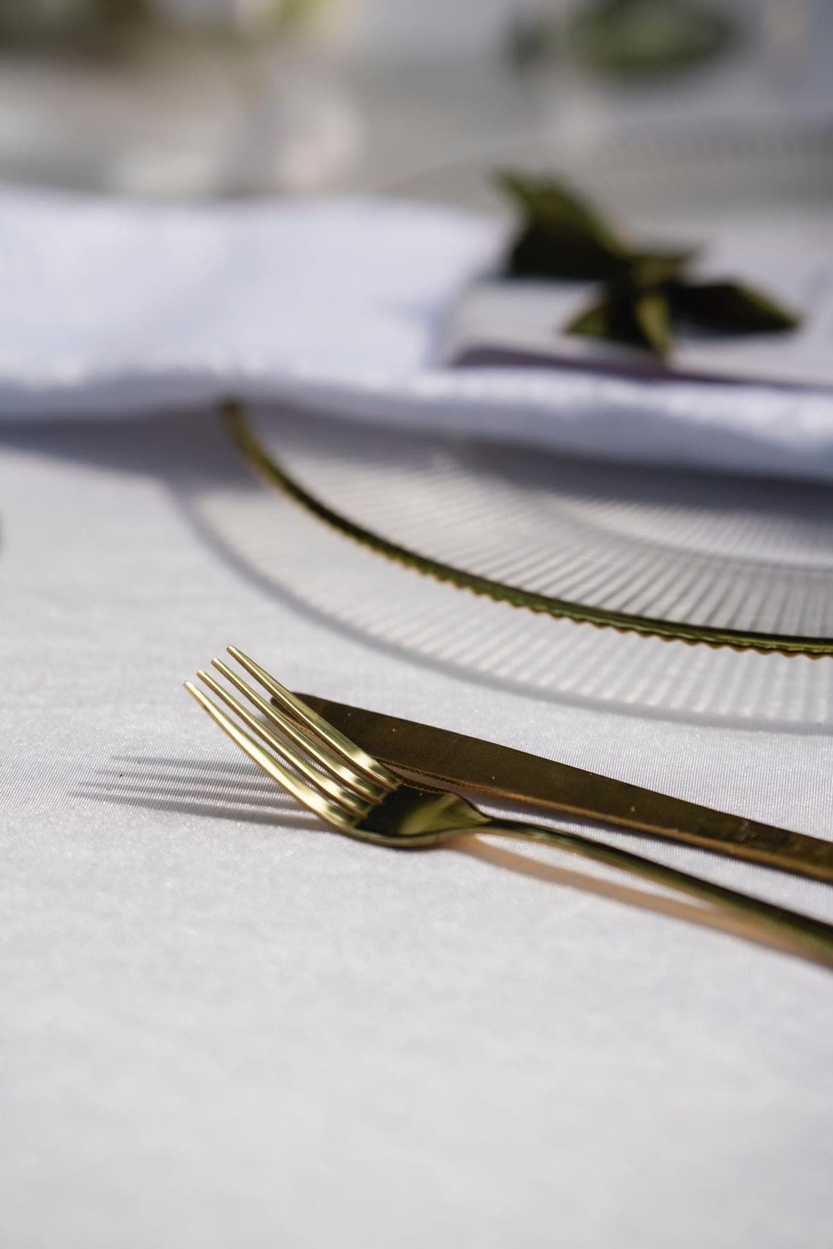 Gold cutlery laid on white linen