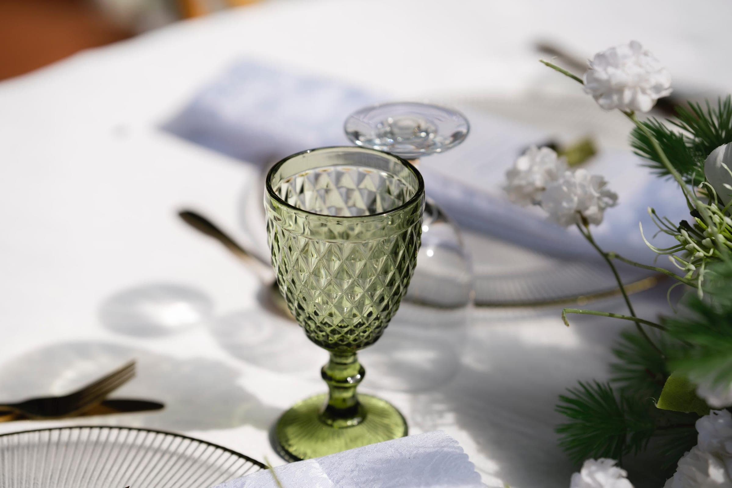 Green glassware and greenery on a white tablecloth
